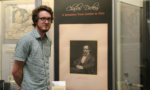 Kevin Dennis '15 with the Charles Dickens exhibit he helped curate at Alden Library.