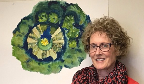 Dr. Theresa Moran, Food Studies Theme Director, stands next to student art depicting a garden where students grow produce now offered in campus venues. 